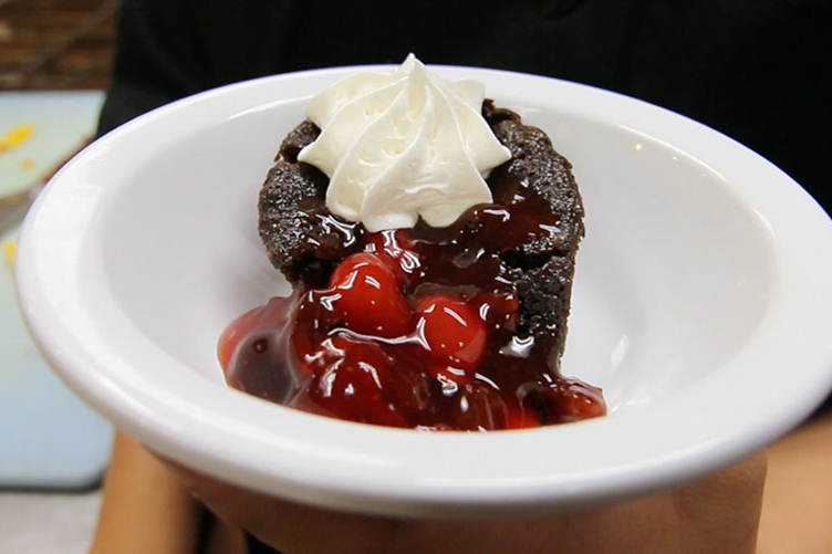 a chocolate brownie dessert with cherries and whip cream