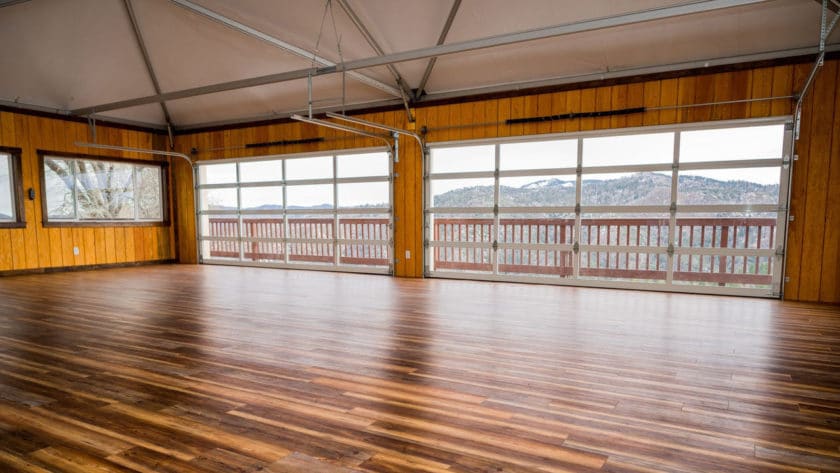 A large room with a wooden floor and large windows showing a mountain view.