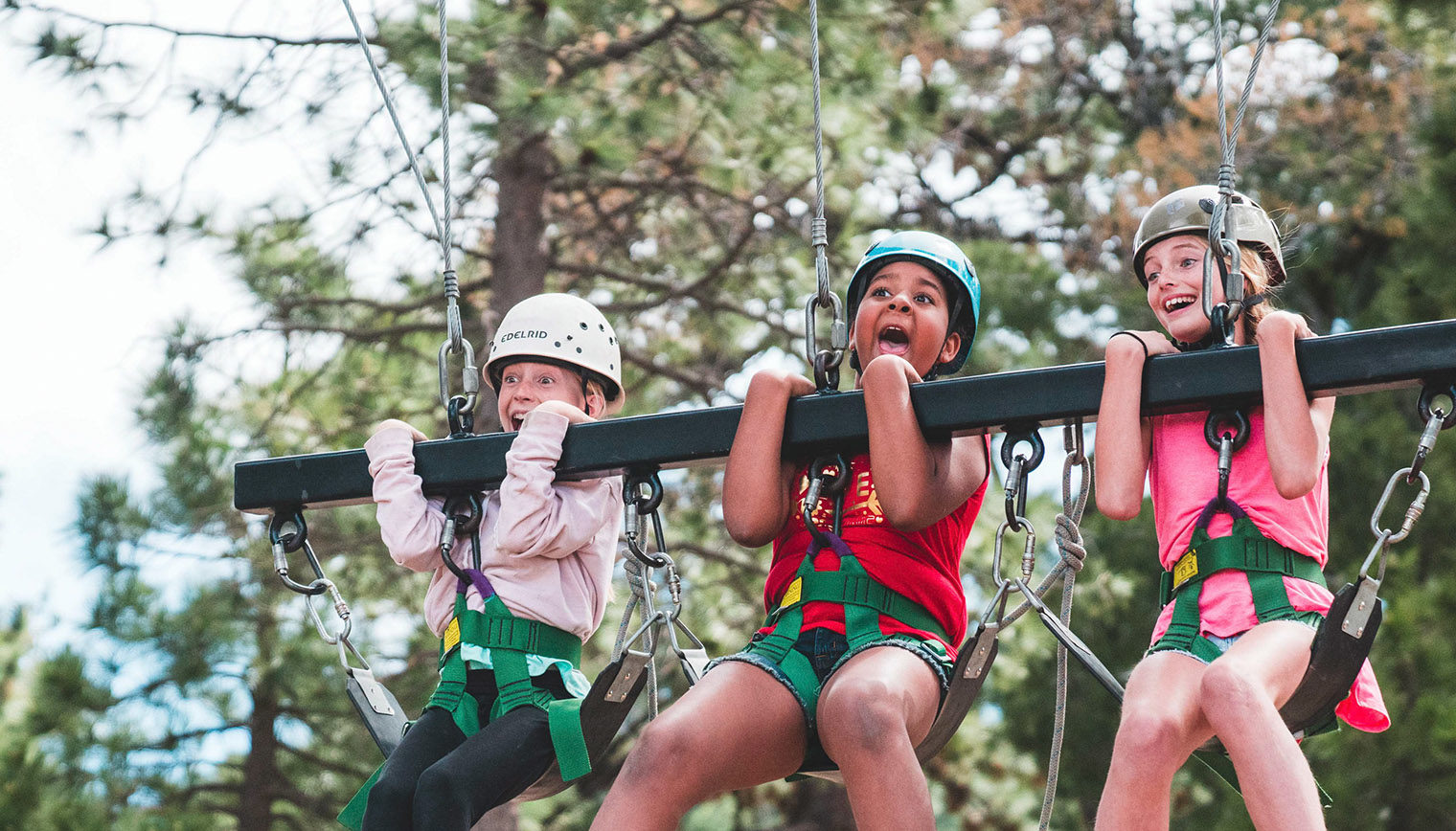 Three girls excited to be on a triple swing.