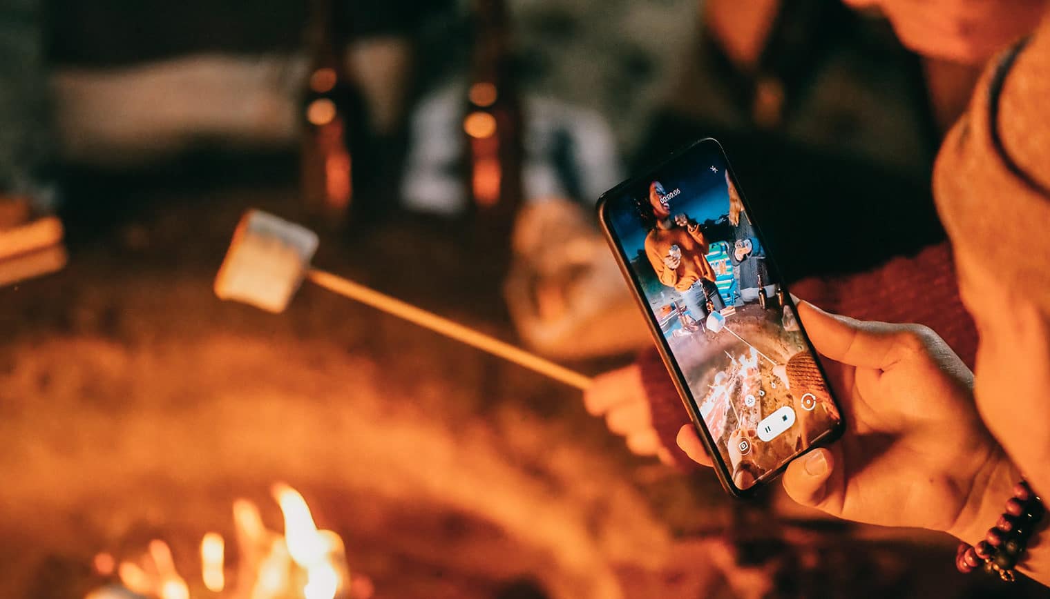 A person filming a video of a toasted marshmallow on a smartphone.