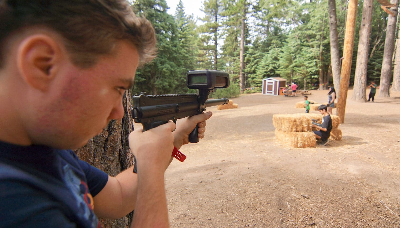 A close up of a boy aiming a laser tag gun.