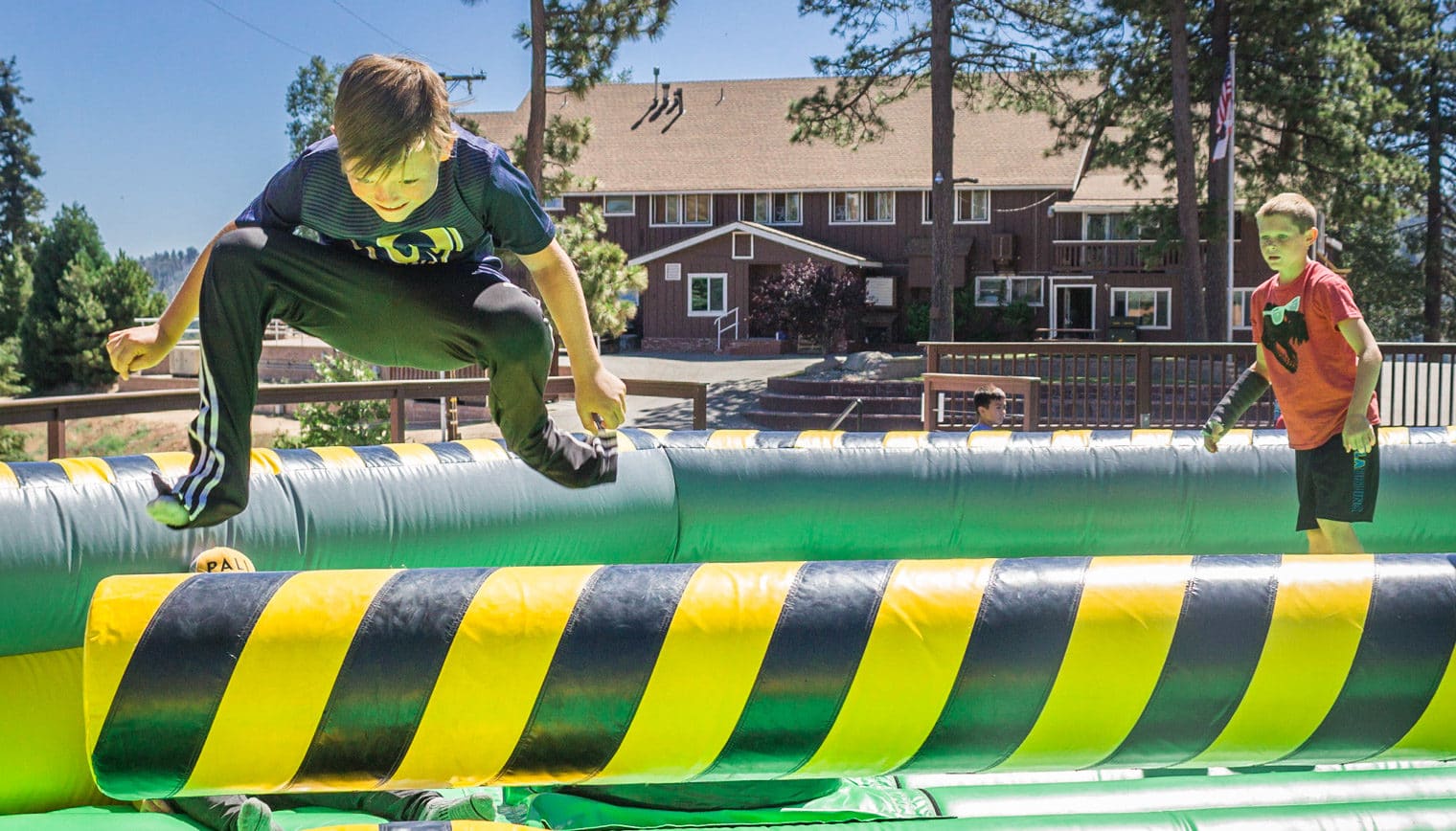 A boy jumping over an inflatable obstacle.
