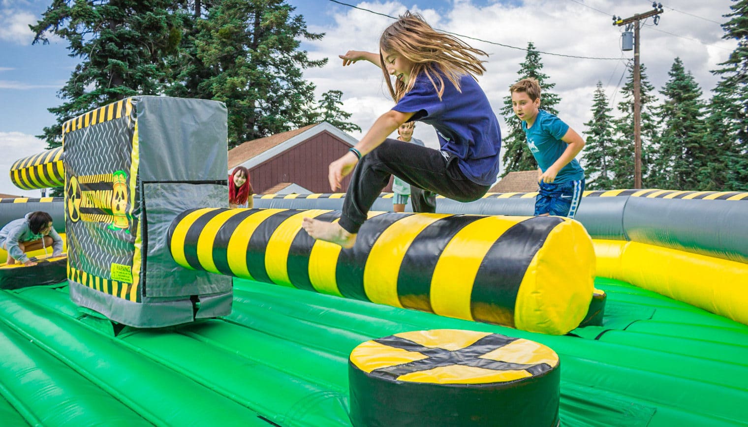 A girl jumping over a inflatable obstacle.
