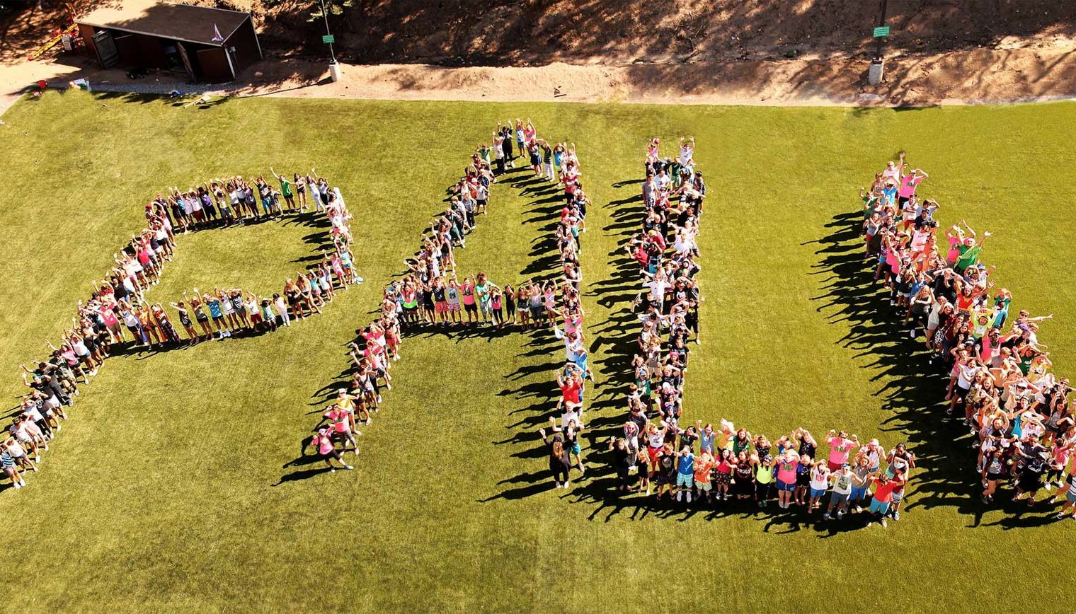 An aerial view of people lined up to spell out PALI.