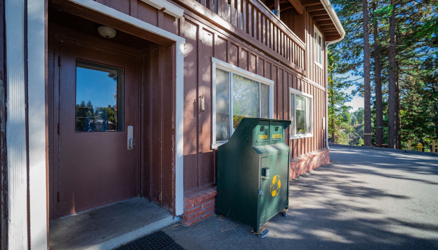 The side of the Lodge exterior with a trash and recycling dump.