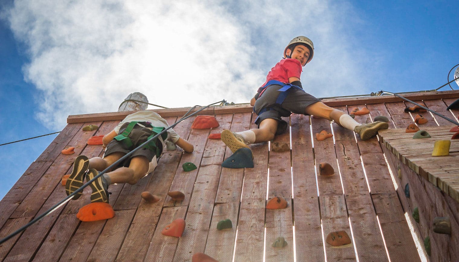 Two teenagers at the top of a rock climbing wall.